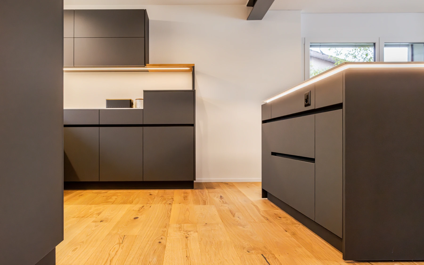 Moderne Küche mit Kochinsel, dunklen Fronten und klarer Raumwirkung.