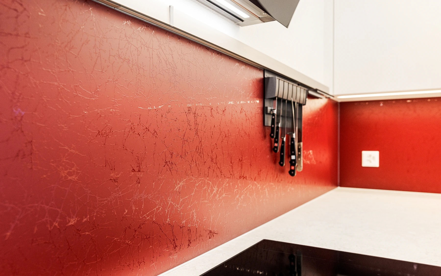 Detail der roten Glasrückwand mit Reling und Beleuchtung