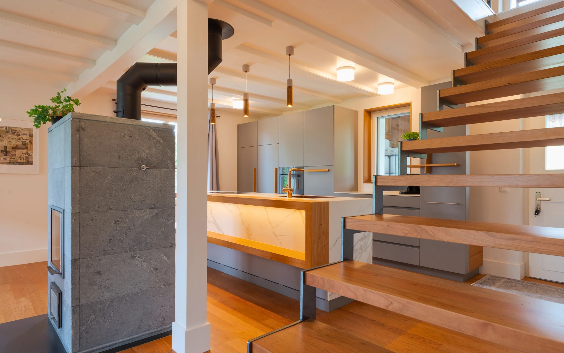 Offene Küche mit fliessendem Übergang zum Wohnraum und Treppe als verbindendes Element.